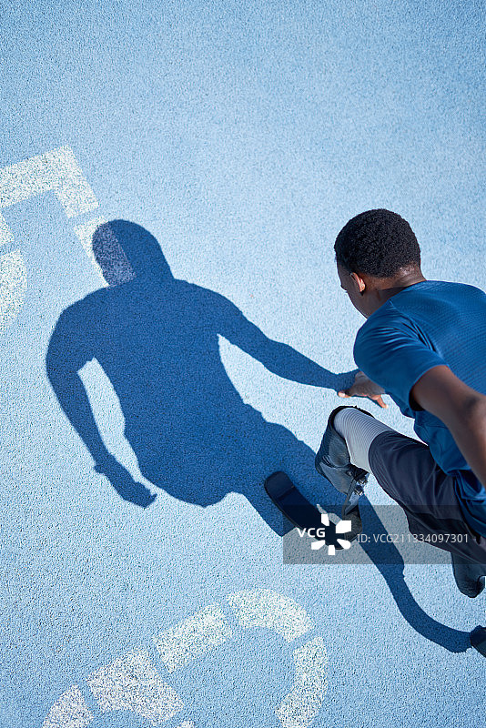 阳光明媚的蓝色跑道上准备就绪的年轻截肢短跑运动员图片素材