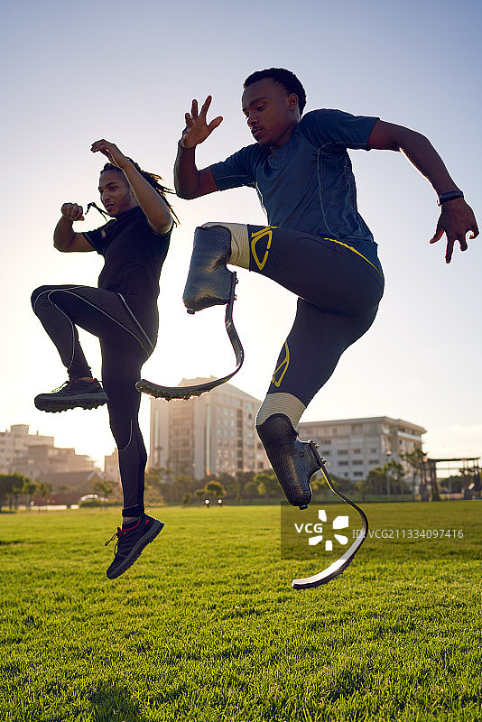 教练和年轻男性截肢运动员在阳光明媚的公园训练图片素材