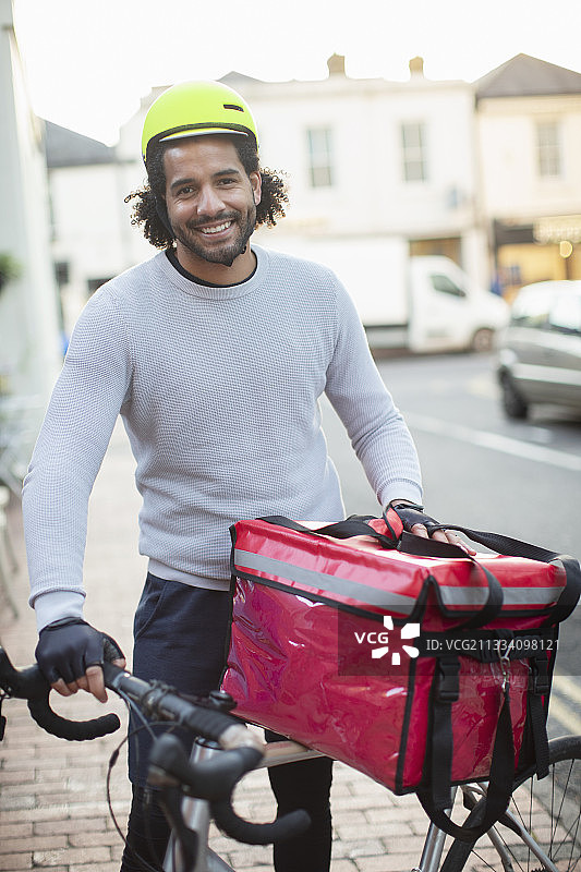 戴着头盔送食物的快乐年轻男性自行车信使的肖像图片素材