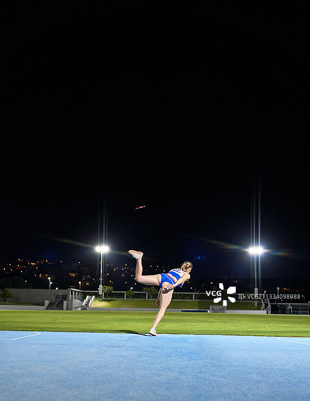 夜晚体育场田径女运动员掷铁饼图片素材