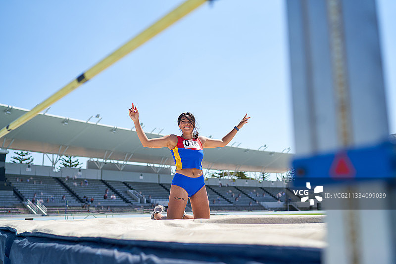 快乐的女田径运动员在高处跳跃图片素材