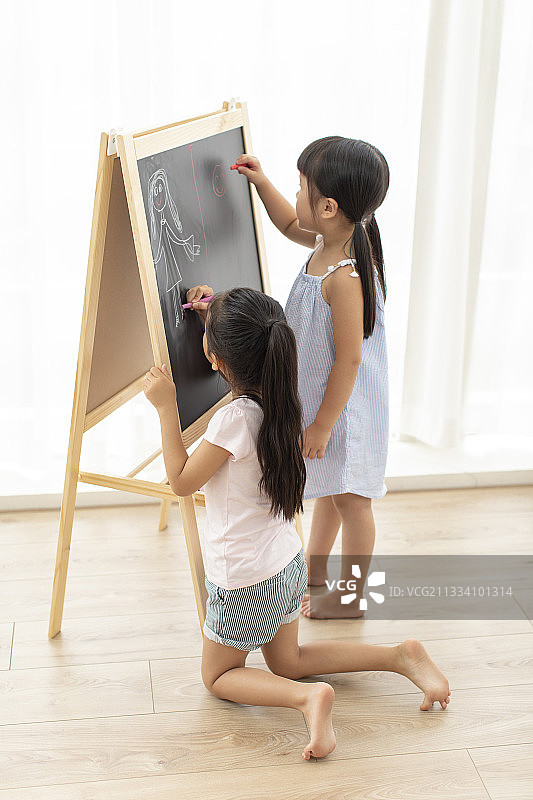 两个小女孩在小黑板上画画图片素材