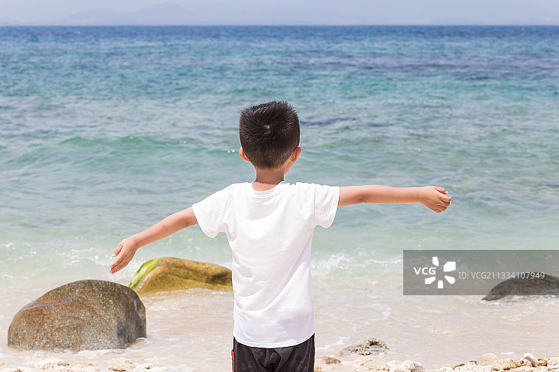 男孩在沙滩上面朝大海图片素材