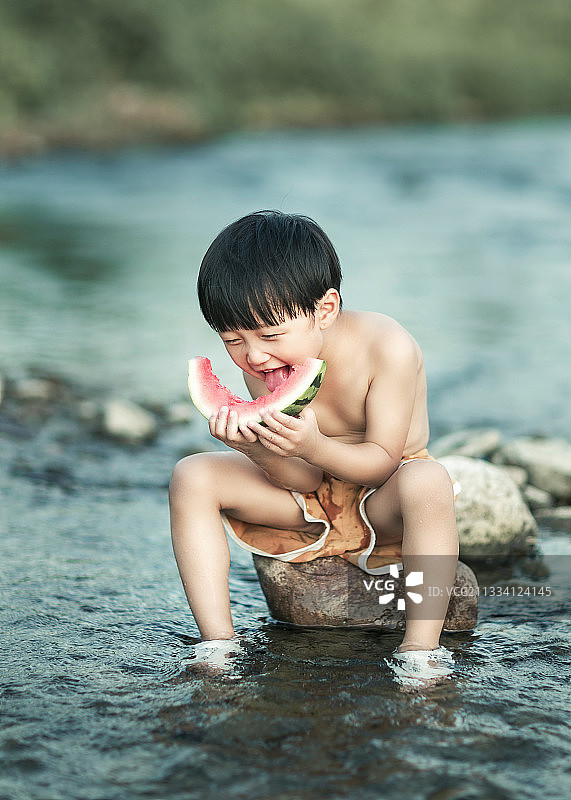 夏天在河边吃西瓜玩水的小男孩图片素材