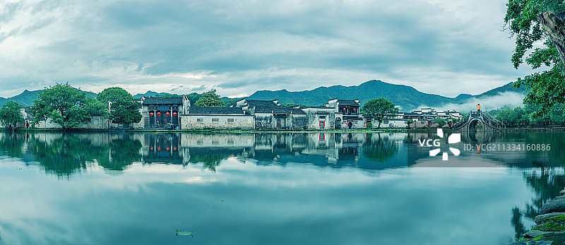 清晨雨后站在宏村南湖拱桥上拍照的人图片素材