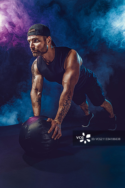 健壮的胡须男运动员正在健身，用健身球做俯卧撑图片素材