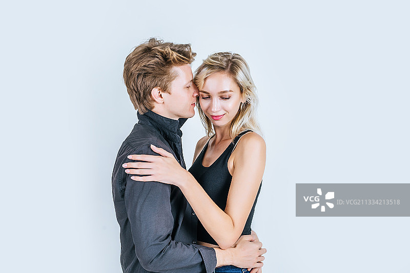 年轻情侣在灰色背景下拥抱的侧视图图片素材