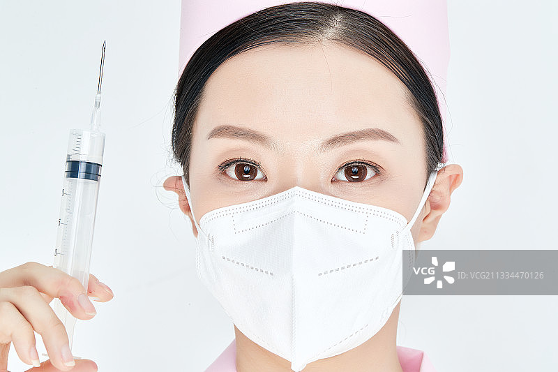 穿护士服戴口罩手执针筒的年轻女护士图片素材