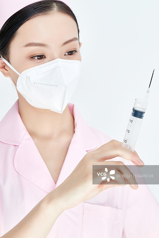 穿护士服戴口罩手执针筒的年轻女护士图片素材