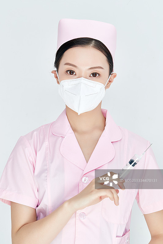 穿护士服戴口罩手执针筒的年轻女护士图片素材