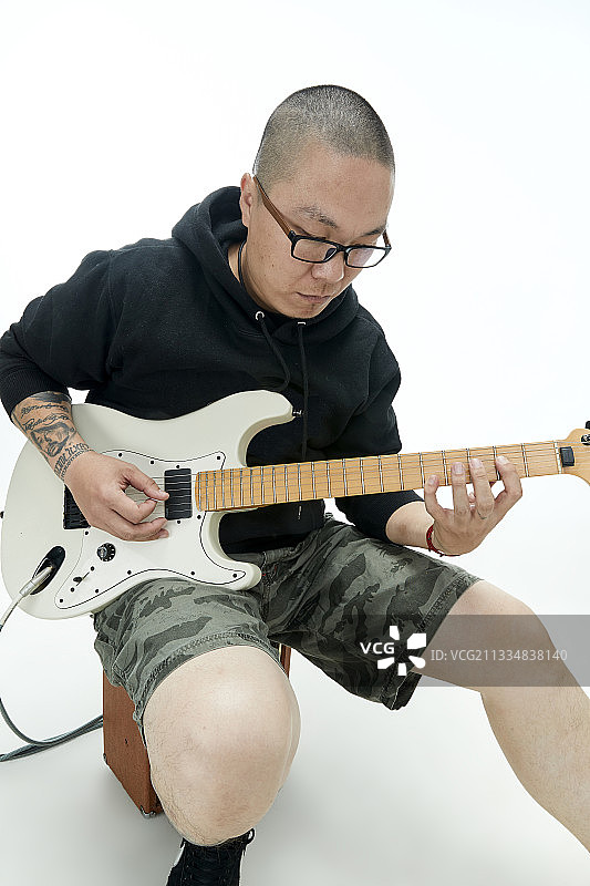 手持电吉他展示演示演奏的亚洲男性摇滚乐手人像图片素材