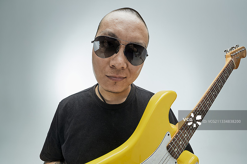 手持电吉他展示演示演奏的亚洲男性摇滚乐手人像图片素材