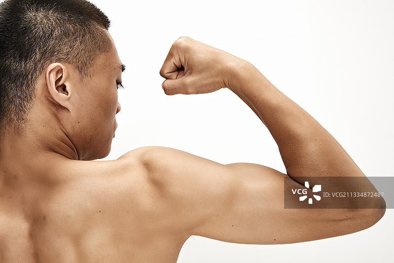白色背景下展示肱二头肌的亚洲健身男性图片素材