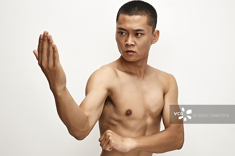 白色背景下演示自由搏击动作的亚洲功夫男性图片素材