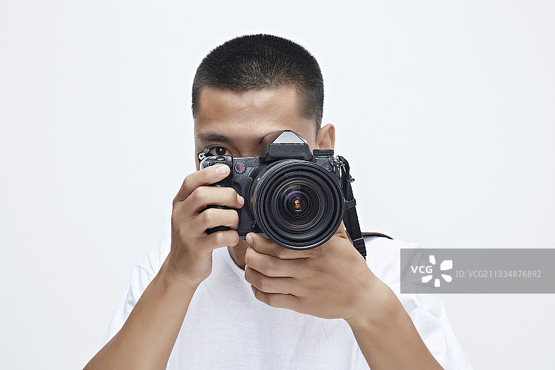 白色背景下手持照相机的亚洲男性摄影师图片素材