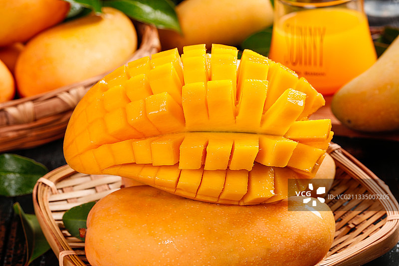 黑石板上放着一筐切开的海南大芒果图片素材