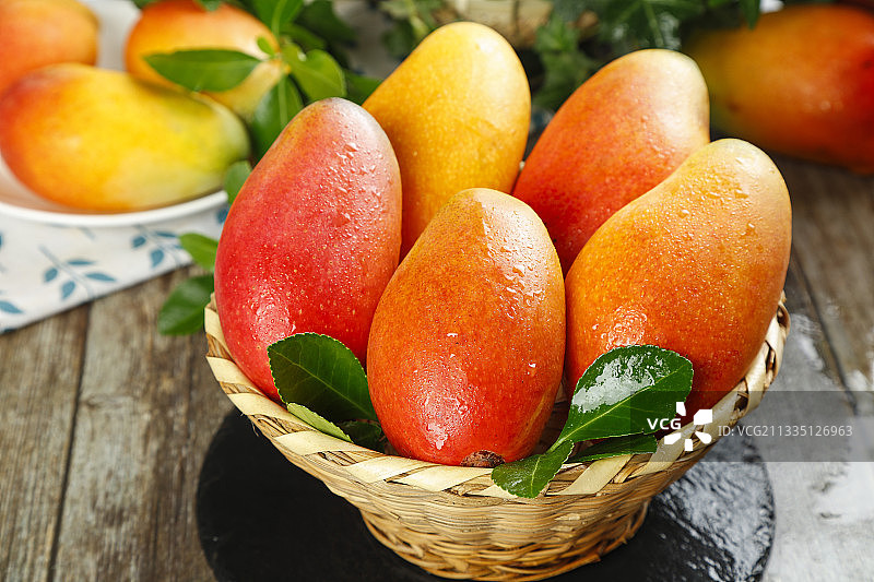 石板上放着一筐新鲜的贵妃芒图片素材