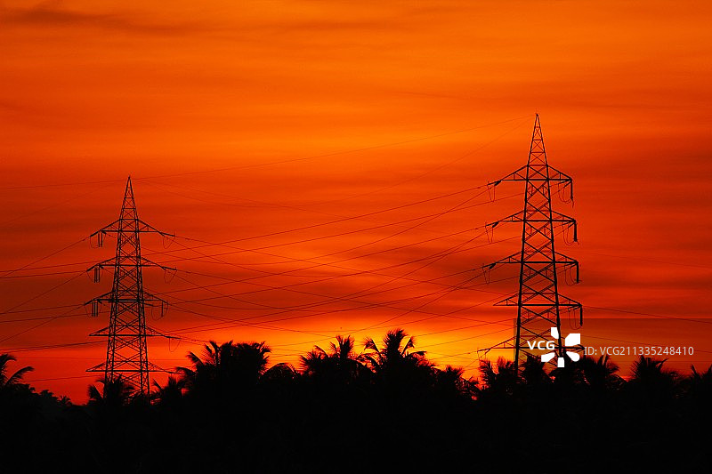 低角度拍摄日落时天空下的电塔轮廓图片素材