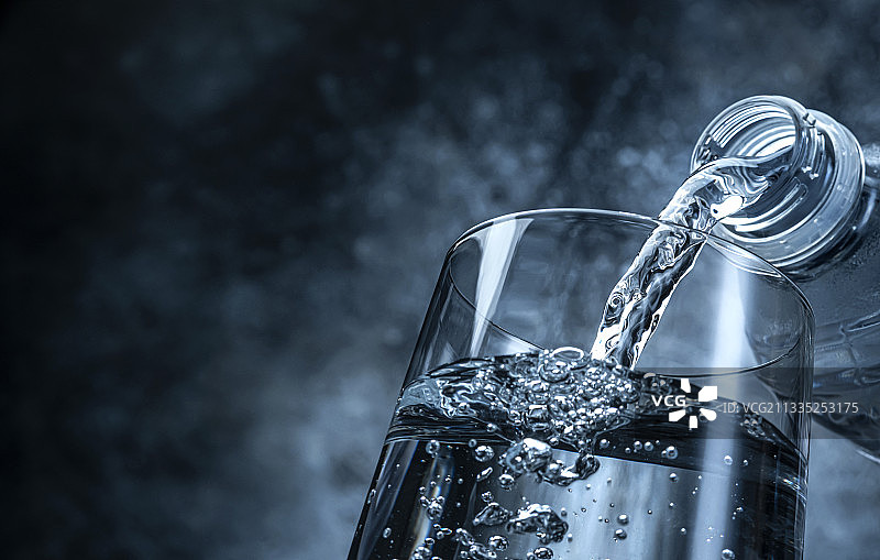 黑色背景下倒入玻璃杯中的水特写图片素材
