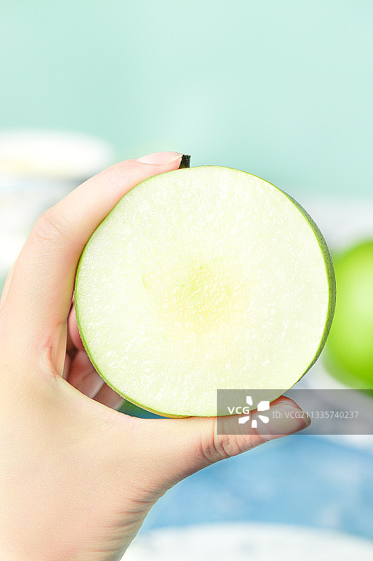 蓝底上手拿一个砀山苹果梨图片素材