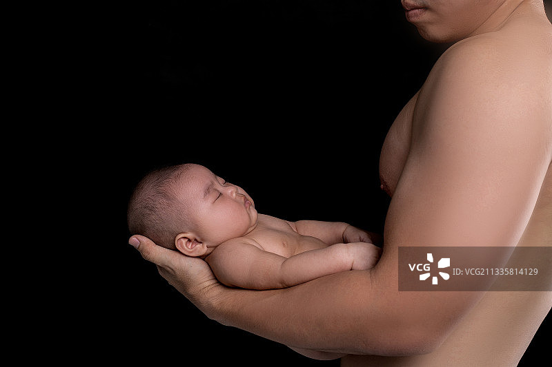 婴儿在强壮父亲的手中安睡图片素材