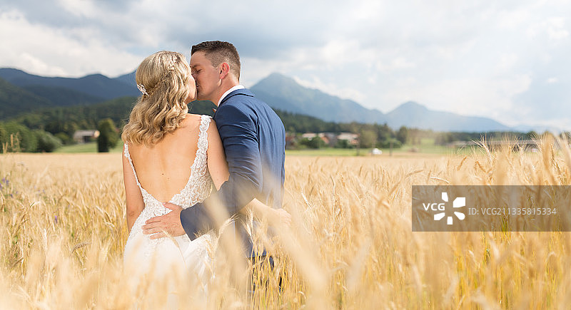斯洛文尼亚麦田里深情拥吻的新娘和新郎图片素材