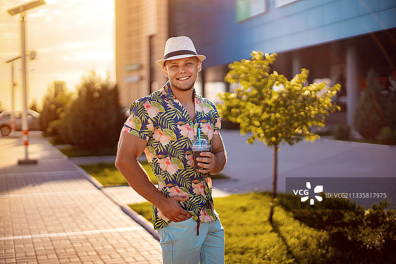 夏装年轻男人在城市风景中喝苏打水肖像图片素材