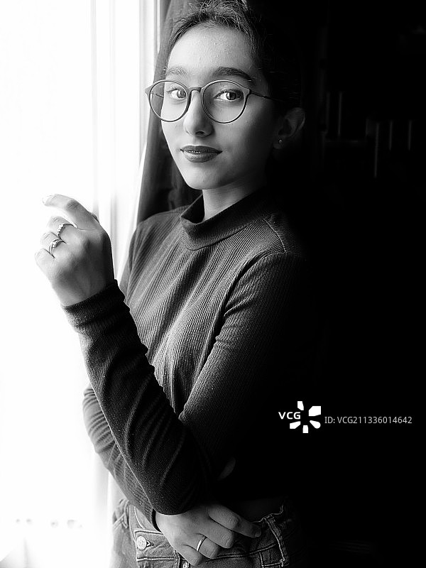 在家中窗边站立的年轻女子肖像图片素材