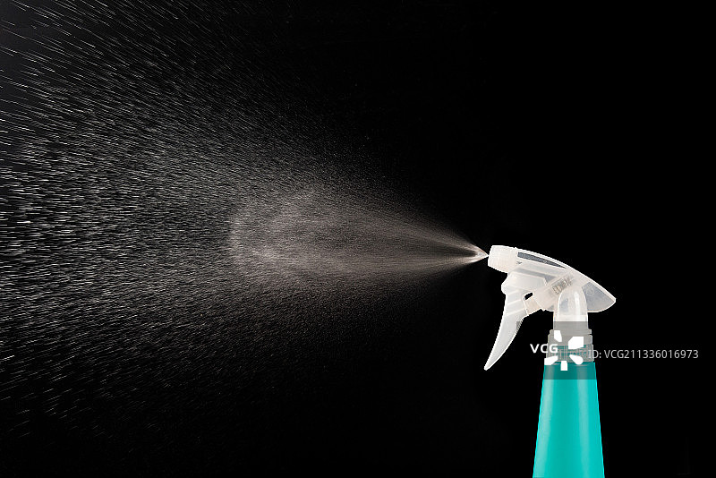 一只喷水的喷壶，黑色背景图片素材