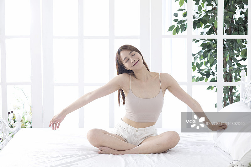 一位美女在卧室起床后愉快的做伸展操图片素材