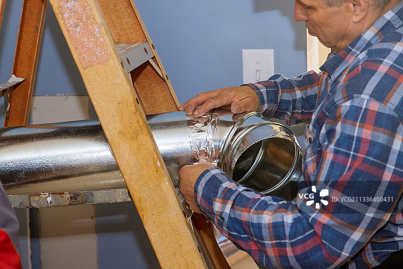 男人在室内天花板下安装空调系统图片素材