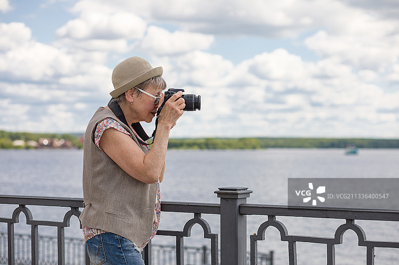 一位在夏日城市堤坝上拍照的老妇人图片素材