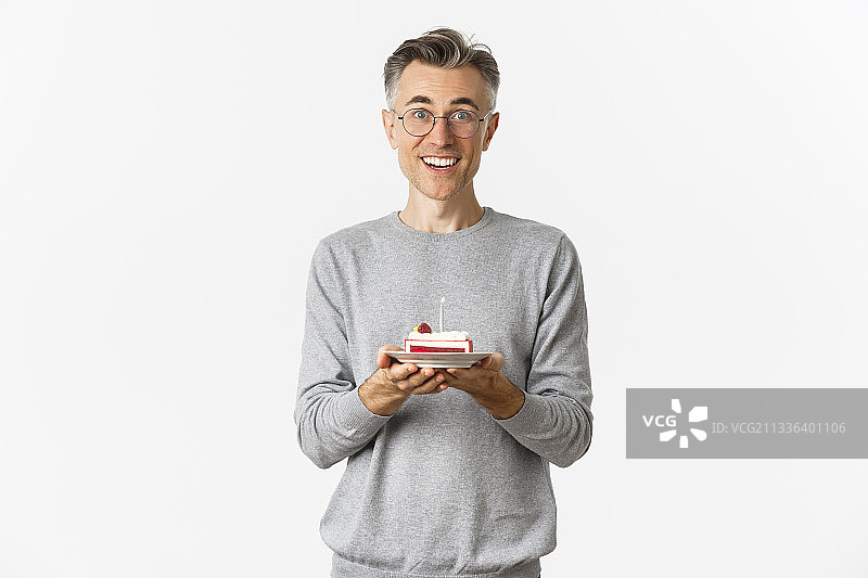 面带微笑的男子拿着蛋糕站在白色背景前的肖像照图片素材
