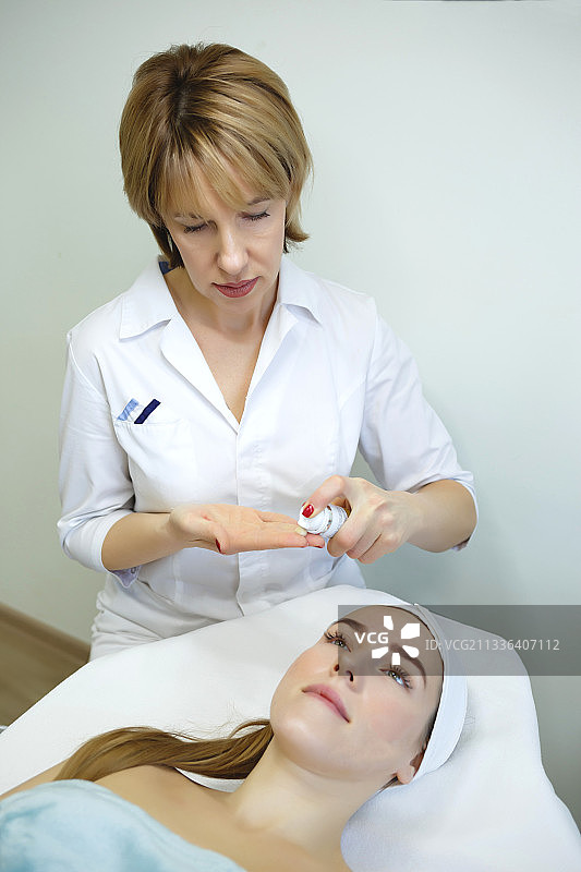 年轻女人在水疗中心接受按摩和面部护理图片素材