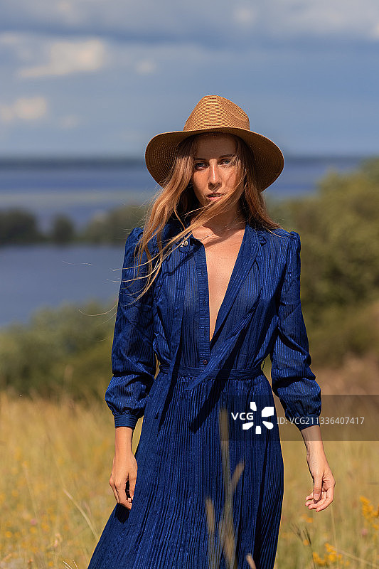 站在田野上对着天空戴帽子的年轻女子肖像，乌克兰图片素材