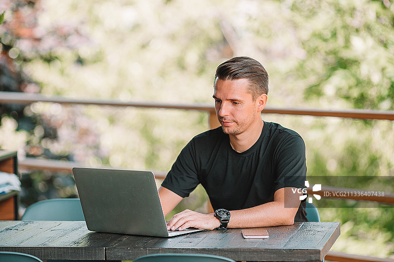 男人在咖啡馆的桌旁使用笔记本电脑图片素材