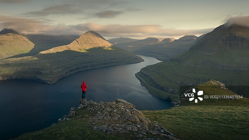 在Hvithamar欣赏峡湾日落全景的男人，法罗群岛图片素材