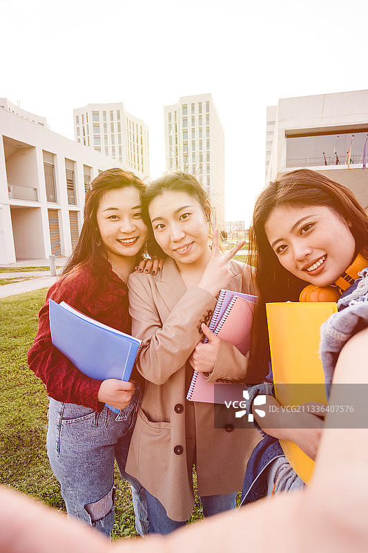 在人行道上拿着书微笑的朋友们的肖像，背景是天空图片素材