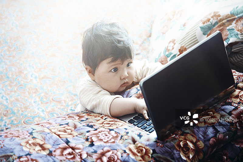 一位一岁大的孩子在父母不在家时使用笔记本电脑图片素材