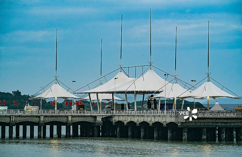 暮色里的海港。白色顶蓬象一顶顶白帽子排列在引桥上。图片素材