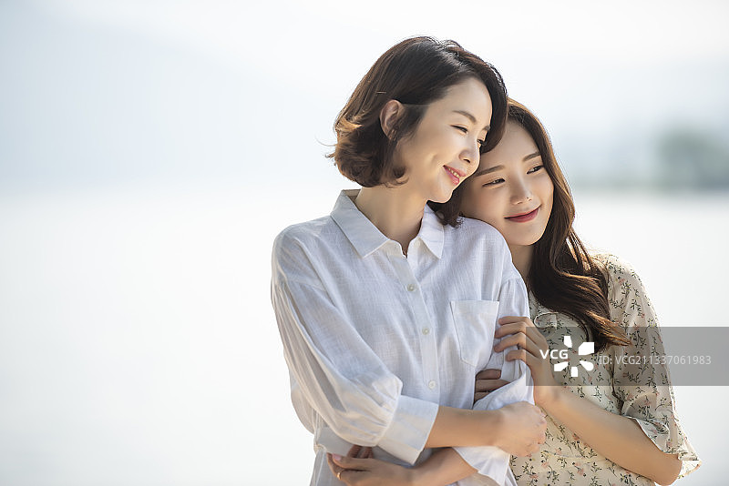 女儿依偎母亲河边微笑图片素材