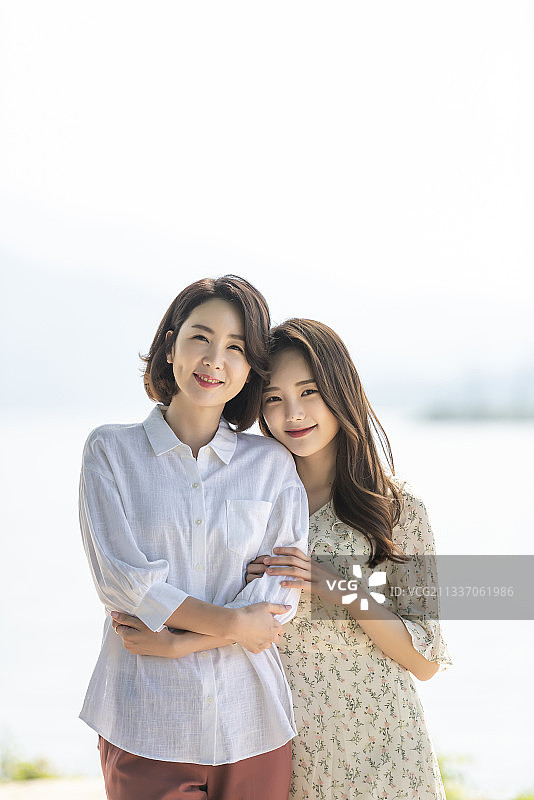 女儿依偎母亲河边微笑图片素材