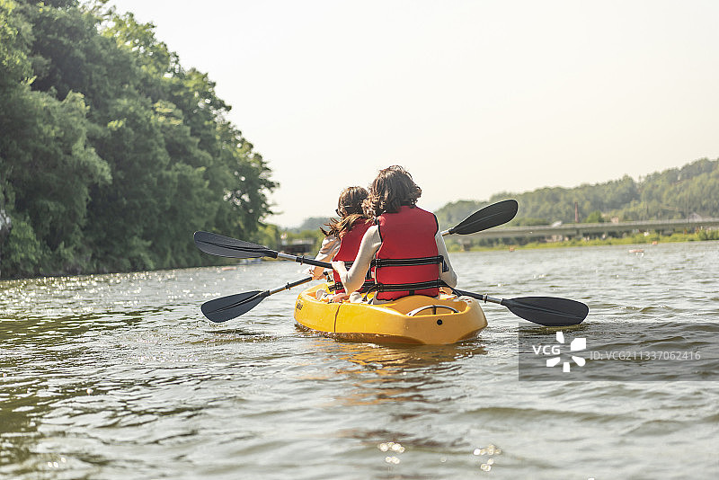 两名戴着太阳镜和救生衣的女子在河上划皮划艇图片素材