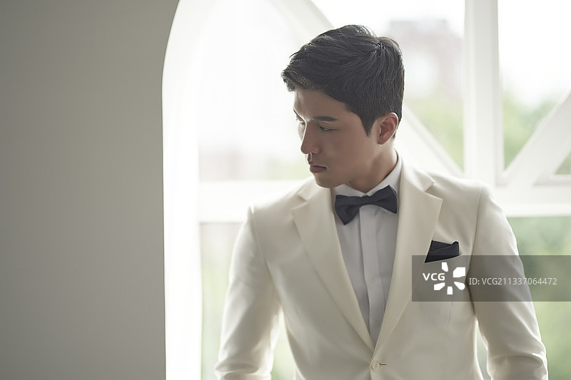 身穿白色燕尾服套装男子站在窗边看向侧面的影棚照片图片素材