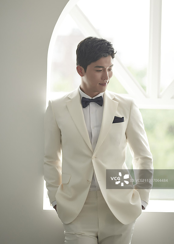 身穿白色燕尾服套装男子站在窗边看向侧面的影棚照片图片素材
