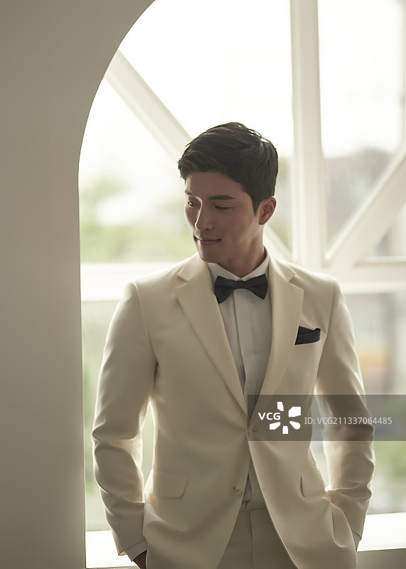 身穿白色燕尾服套装男子站在窗边看向侧面的影棚照片图片素材