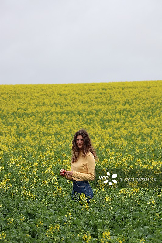 站在鲜花盛开的田野中的微笑女性肖像图片素材