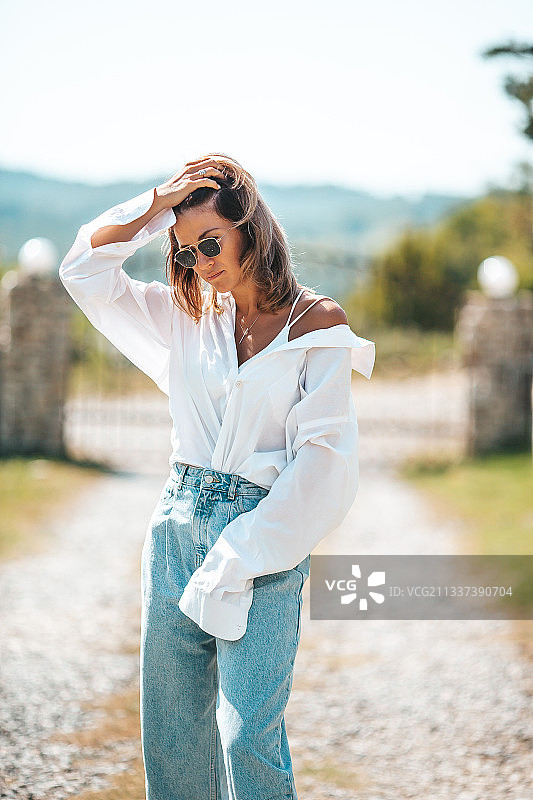 戴太阳镜的年轻女人站在人行道上图片素材