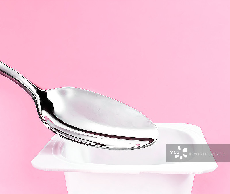 粉色背景上的酸奶杯和银勺图片素材