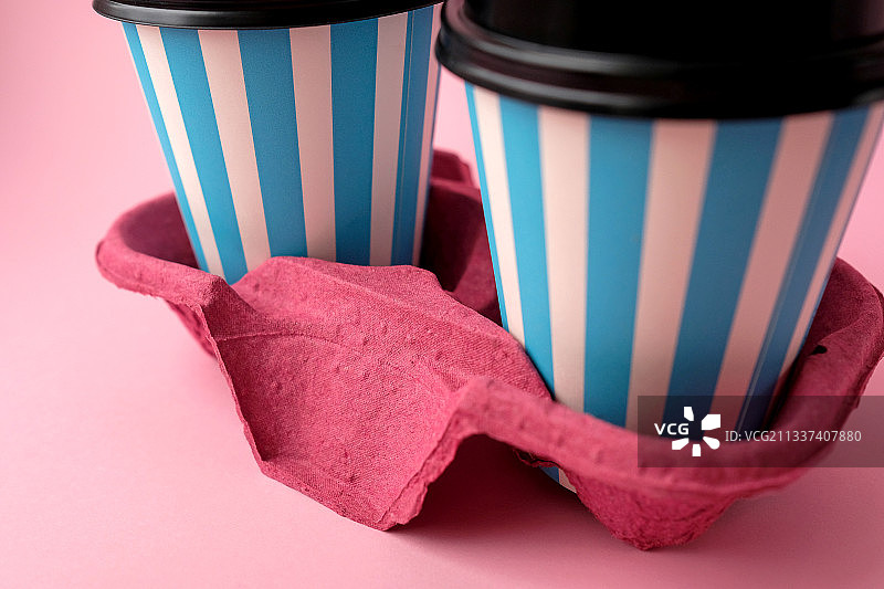 粉色背景上的带杯托的一次性杯子特写图片素材